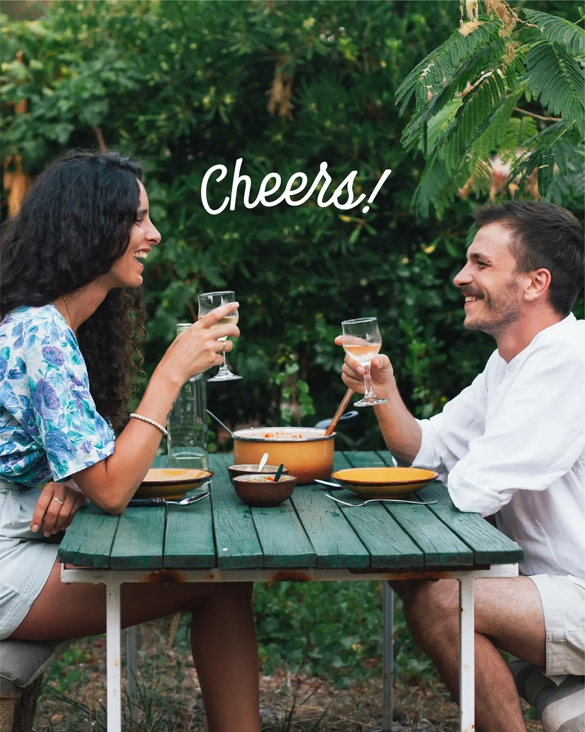 A couple toasting at an outdoor lunch, paid for with their Earthmover checking account
